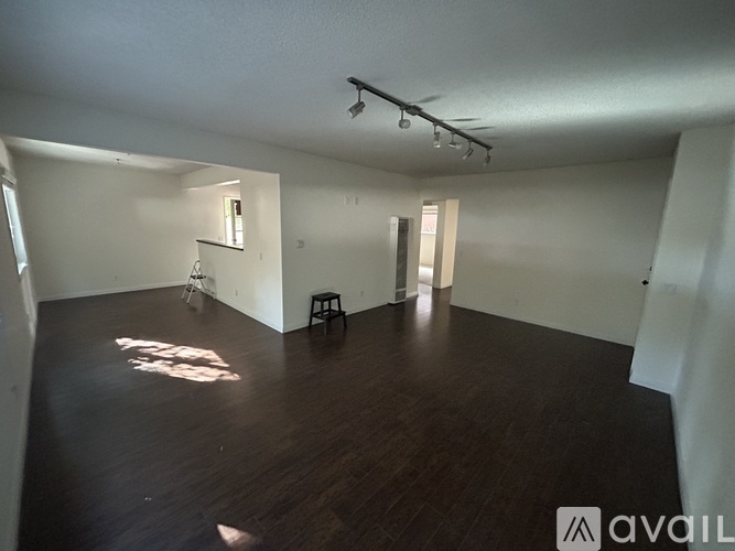 A spacious room with wooden floors and white walls.