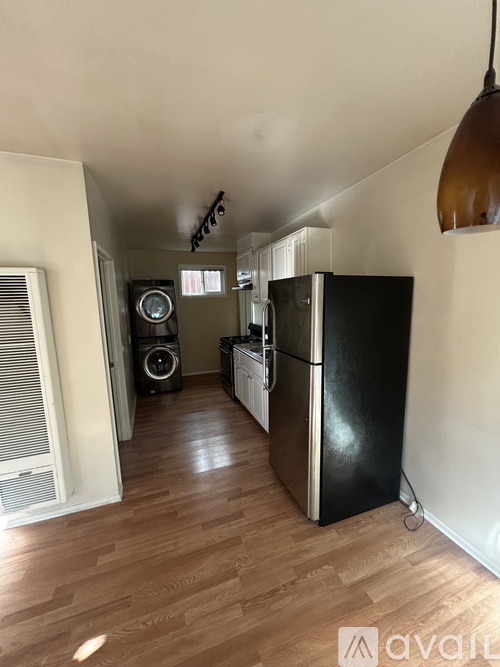A kitchen with a black fridge and wooden floors.