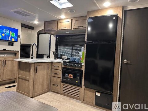 A modern kitchen with wooden cabinets and a black fridge.