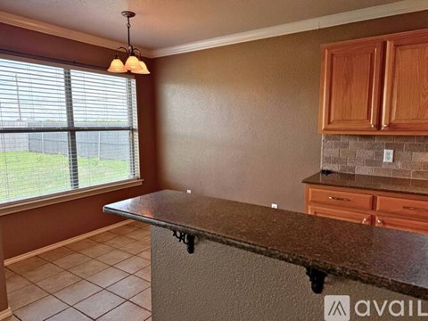 A kitchen with brown cabinets and a granite countertop.