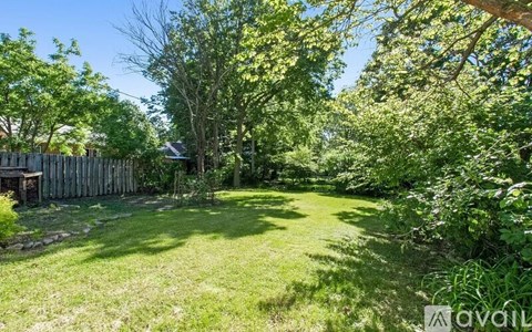 A backyard with a wooden fence and a tree in the middle.