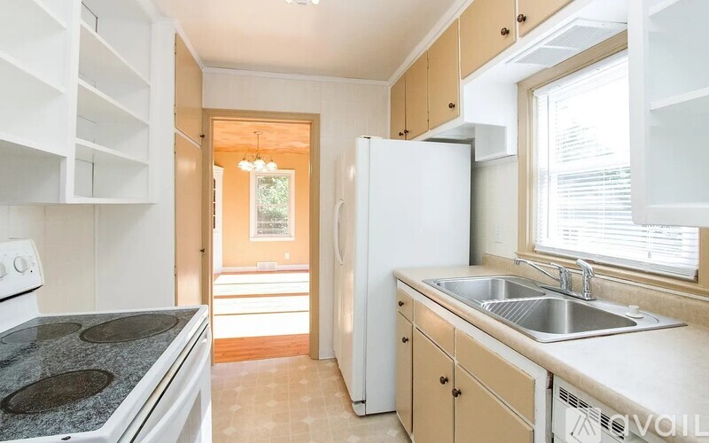 A kitchen with a white fridge, white cabinets, and a black stove top.