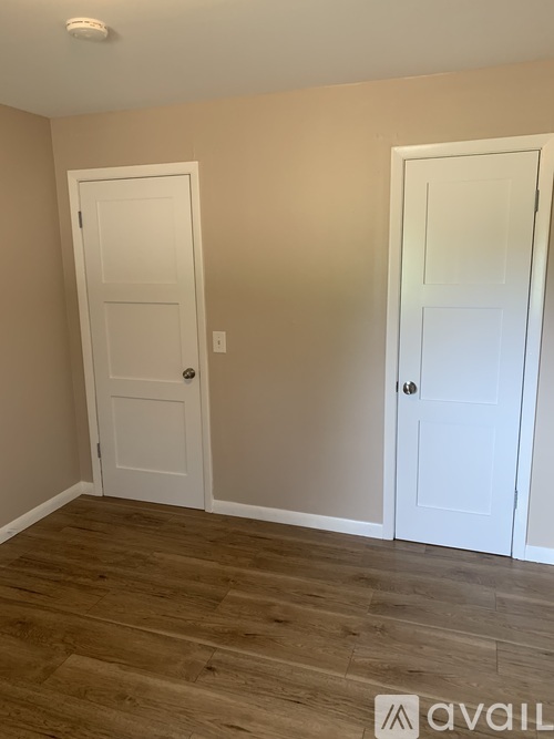 Two white doors in a room with wooden floors.
