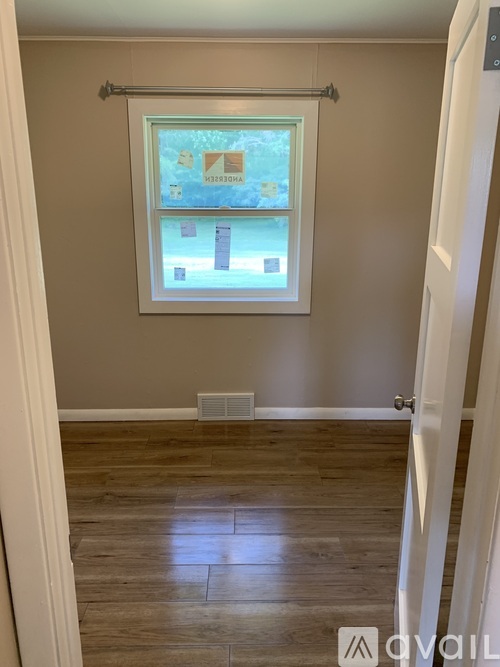 A room with a window and wooden flooring.