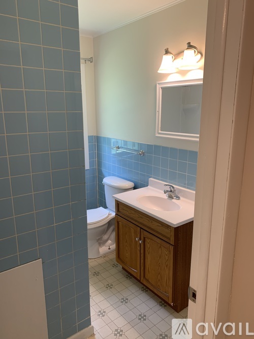A bathroom with a toilet, sink, and mirror.