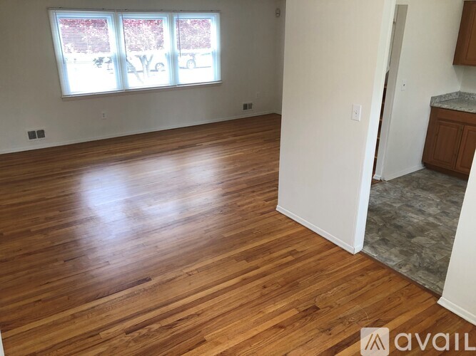 A room with wooden flooring and a window with a view of trees.