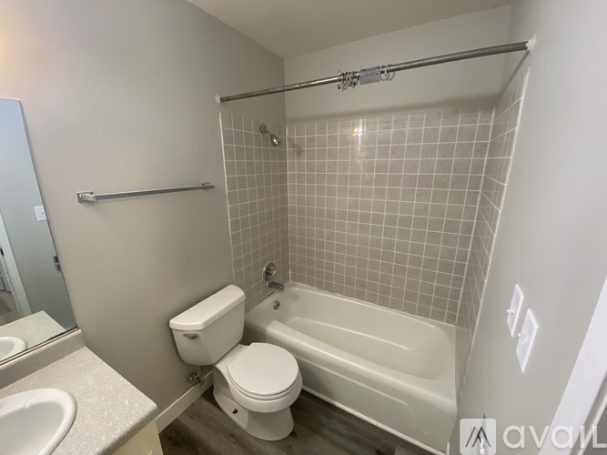 A white toilet sits next to a white bathtub in a small bathroom.