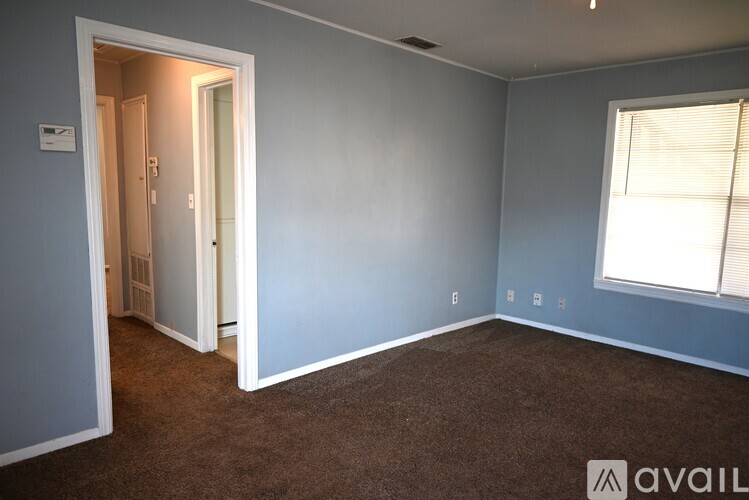 A room with a carpeted floor and a window with blinds.