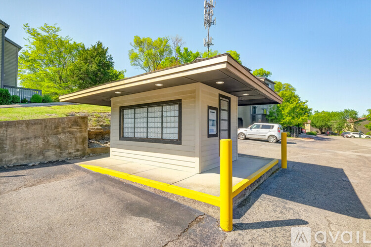 A small building with a yellow border is situated in a parking lot.