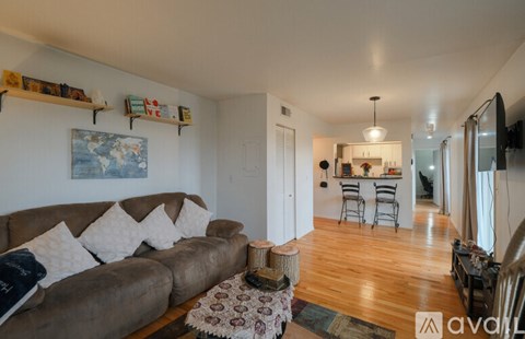 A living room with a brown couch and a rug.
