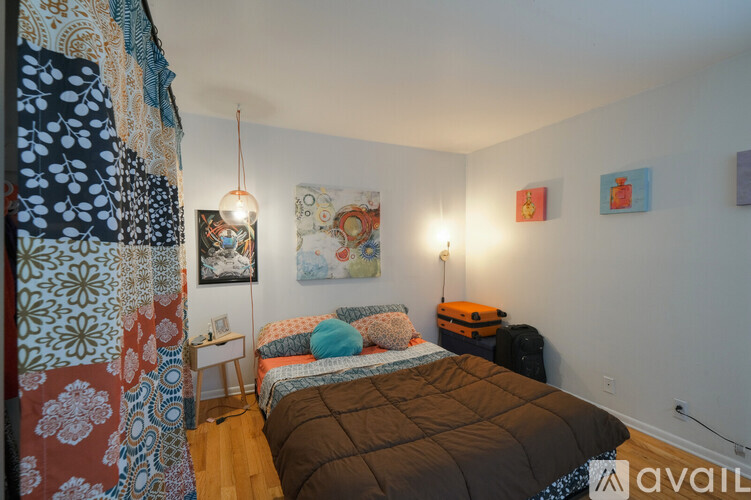 A bedroom with a bed, a nightstand, and a wall hanging.
