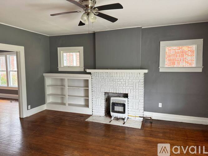 A living room with a fireplace and a ceiling fan.