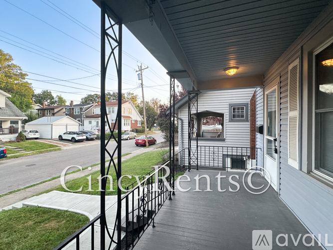 A balcony with a metal railing overlooks a street with cars and houses.