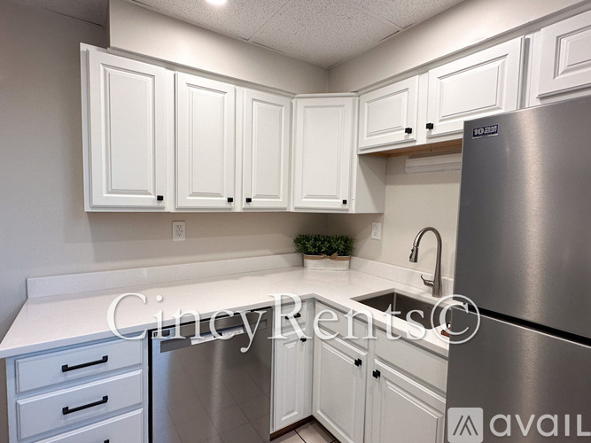 A kitchen with white cabinets and a stainless steel refrigerator.