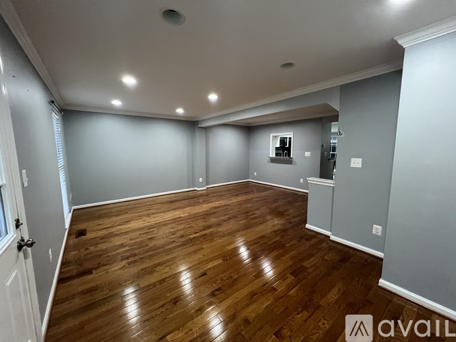 A spacious room with wooden flooring and white walls.