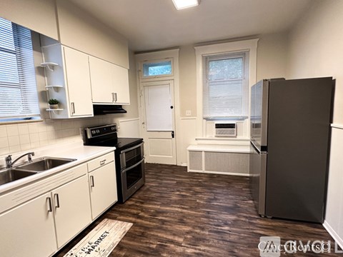 A kitchen with white cabinets and a black fridge.