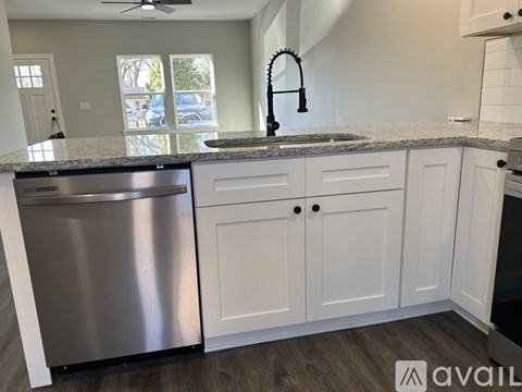 A kitchen with a stainless steel dishwasher and white cabinets.