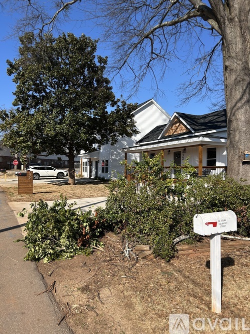 A mailbox is on a white post in front of a bush.