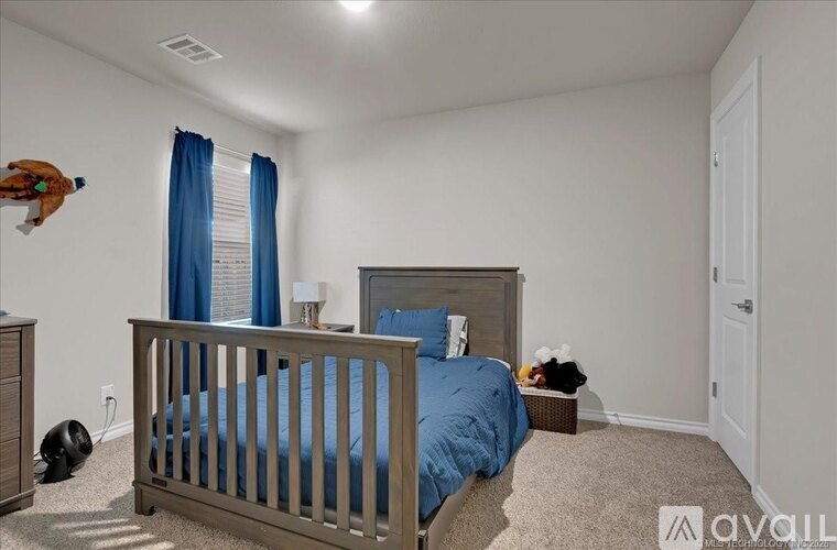A bedroom with a bed, nightstand, and window with blue curtains.