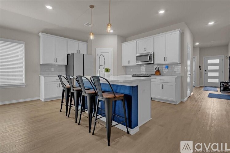 A kitchen with white cabinets and a blue bar stool.