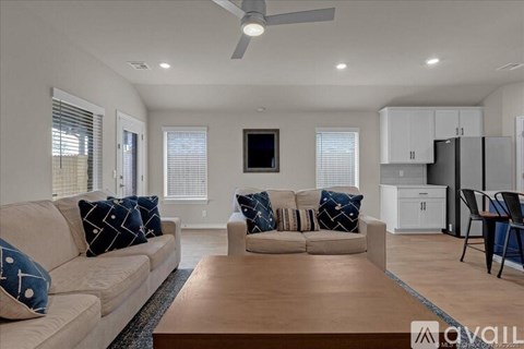 A living room with a beige sofa, a wooden coffee table, and a television on the wall.
