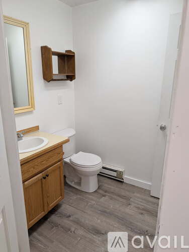 A bathroom with a toilet, sink, and mirror.
