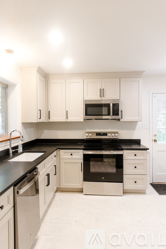 A kitchen with white cabinets and black countertops.