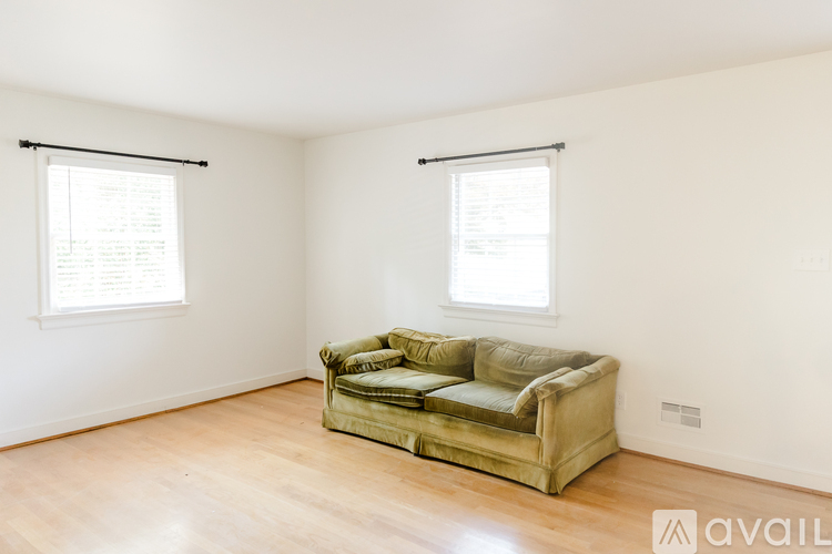 A living room with a green couch and wooden floors.
