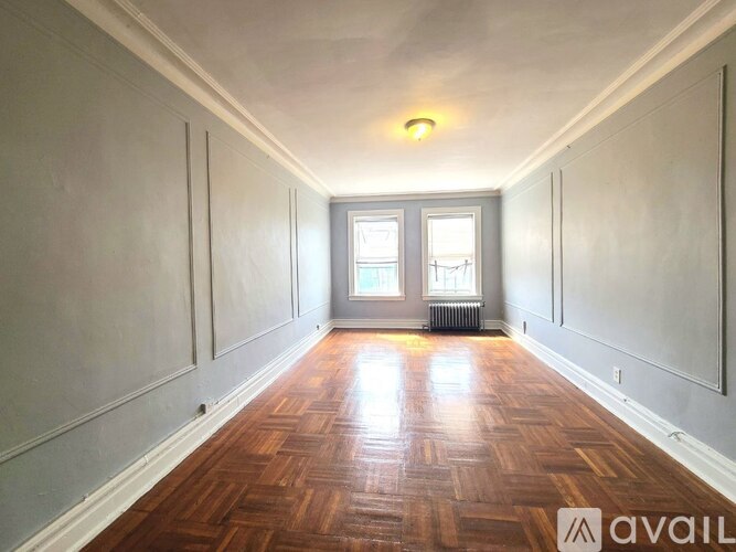 A long hallway with wood floors and a window at the end.