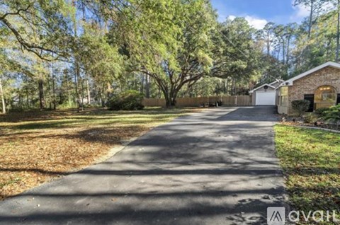 A tree-lined driveway leads to a house.