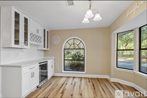 A kitchen with white cabinets and a wooden floor.