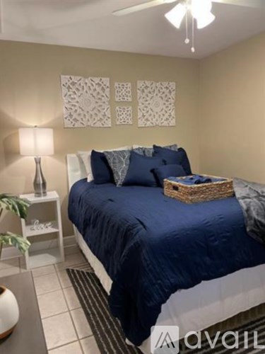 A bedroom with a bed, nightstand, lamp, and wall art.