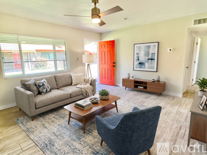 A living room with a grey couch, a blue chair, a wooden coffee table, and a ceiling fan.