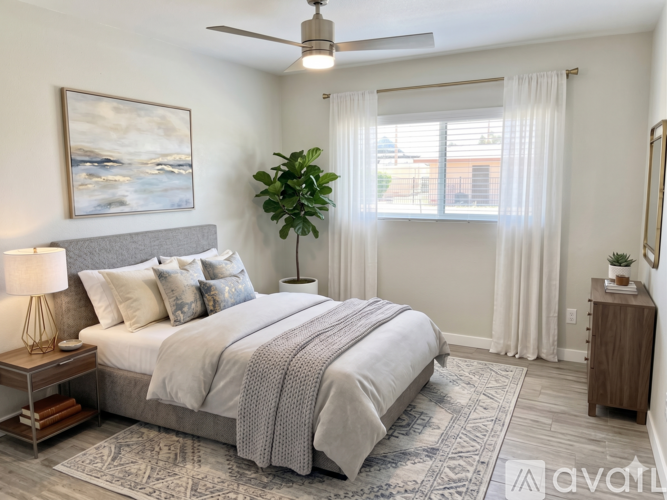 A bedroom with a large bed, a ceiling fan, and a painting on the wall.