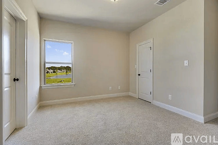 A room with a window that has a view of trees and houses outside.