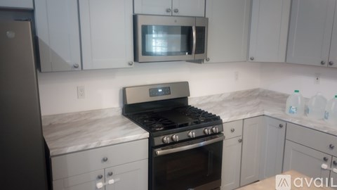 A kitchen with a black stove top oven and a microwave above it.