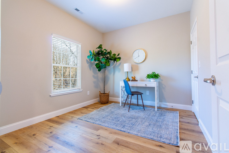 A room with a desk, chair, and plants.