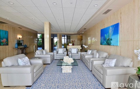 A spacious living room with white furniture and a blue carpet.