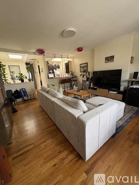 A living room with a white couch and wooden floors.