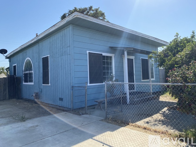 A blue house with a white fence in front.