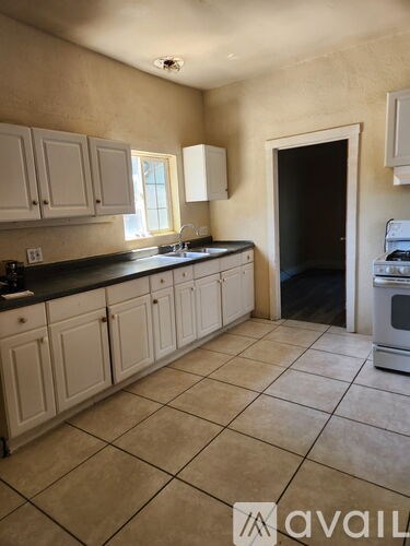A kitchen with white cabinets and a black countertop.