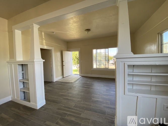 A spacious room with a grey floor and white columns.