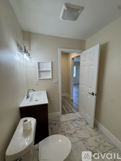 A bathroom with a toilet, sink, and a door.