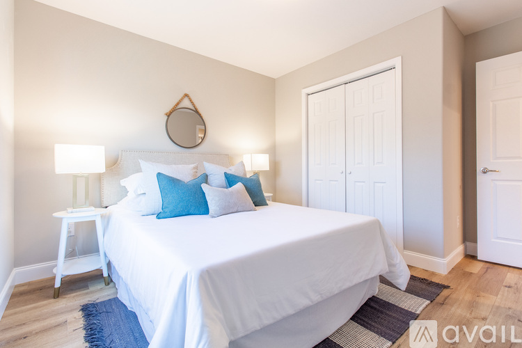 A bedroom with a white bed and blue pillows.