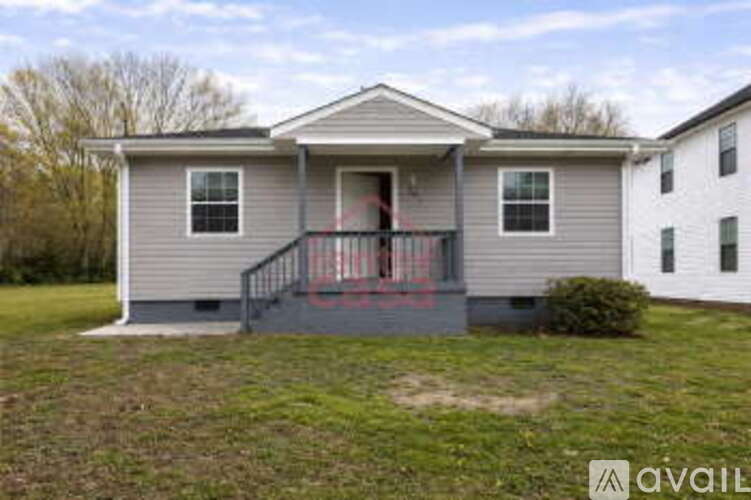 A house with a grey exterior and a red door is for sale.