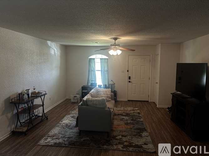A living room with a couch, a television, and a window with curtains.