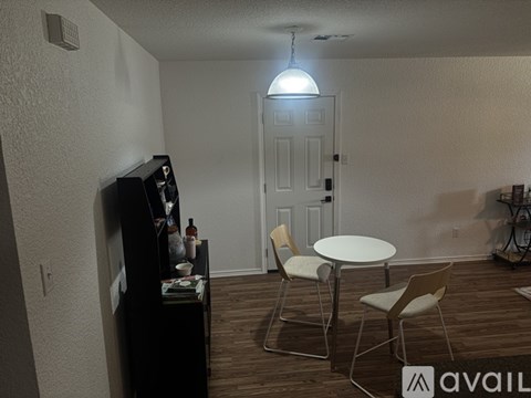 A living room with a white table and chairs, a television, and a door in the background.