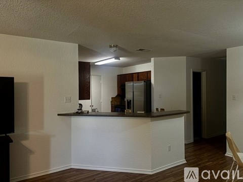 A kitchen with white walls and a wooden floor.