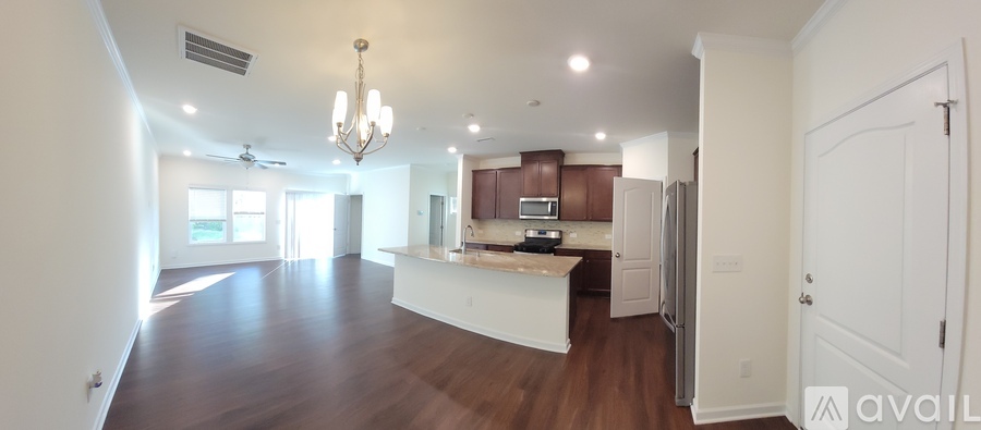 A large, empty living room with a kitchen area in the background.