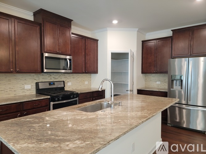 A kitchen with brown cabinets and a marble countertop.
